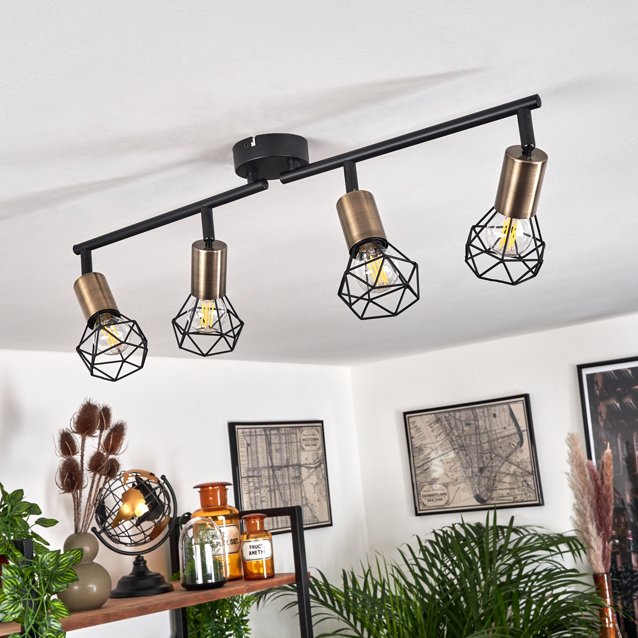 Eine schwarze Deckenleuchte mit vier Lampen und geometrischen Käfigschirmen.