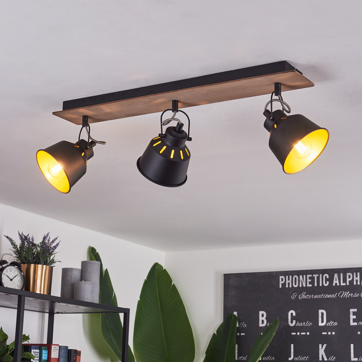 Drei schwarze Lampen mit Holzsockel hängen an der Decke.