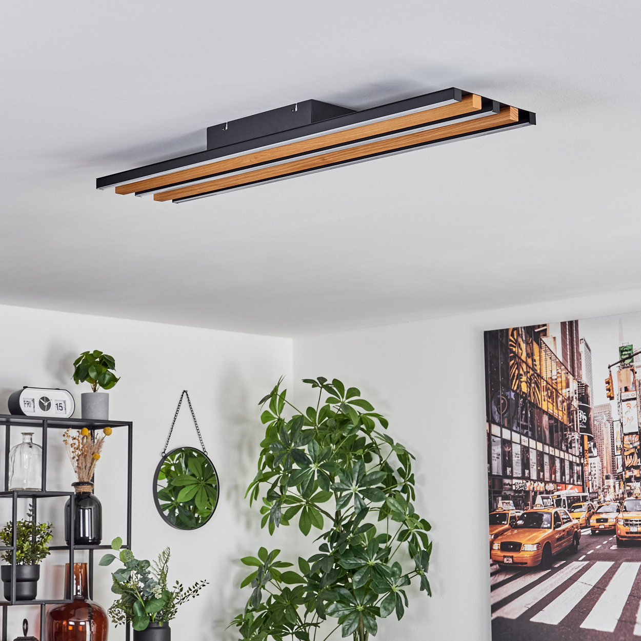 Deckenleuchte mit Holz und Metall, daneben ein Regal mit Pflanzen und ein New York Bild.