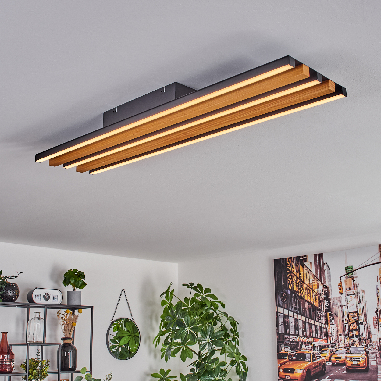 Moderne Deckenleuchte mit Holzlamellen und LED-Beleuchtung, über Regal mit Pflanzen und Spiegel.