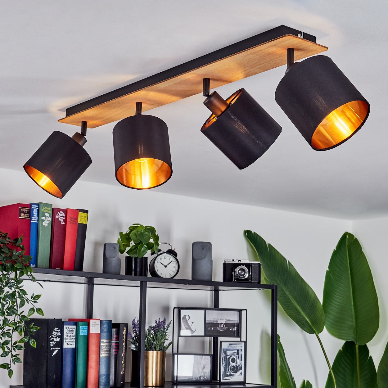 Ein moderner Deckenstrahler mit vier schwarzen Lampenschirmen und Holzbasis.