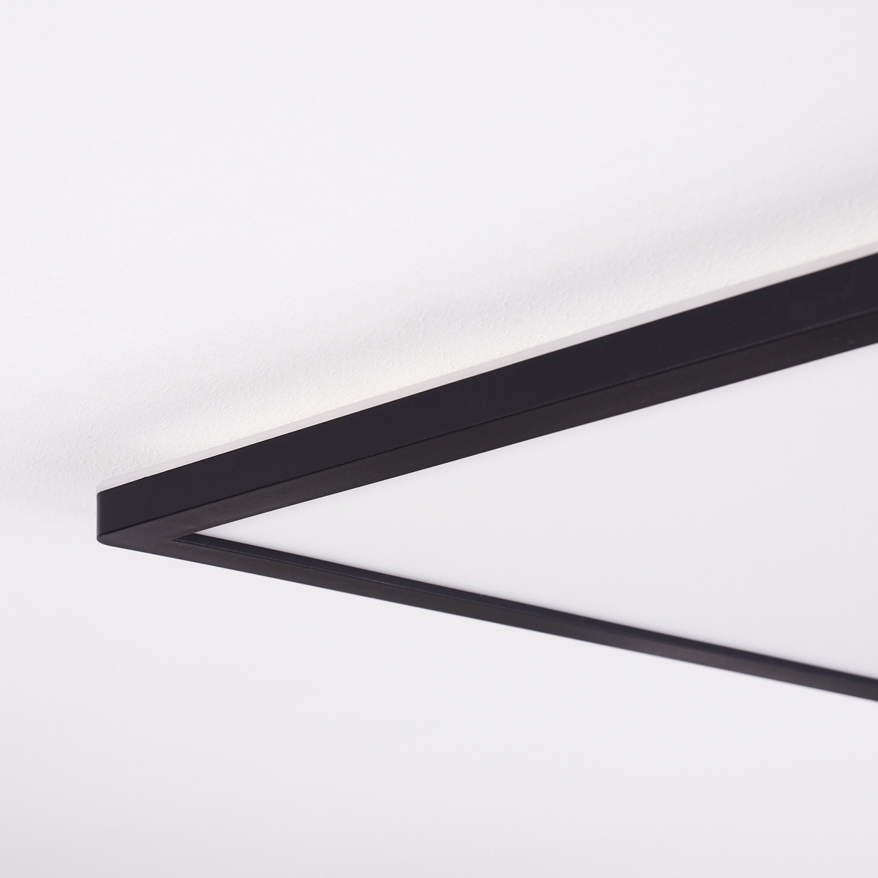 Ein rechteckiges schwarzes Licht mit einem weißen Diffusor, das an der Decke montiert ist.