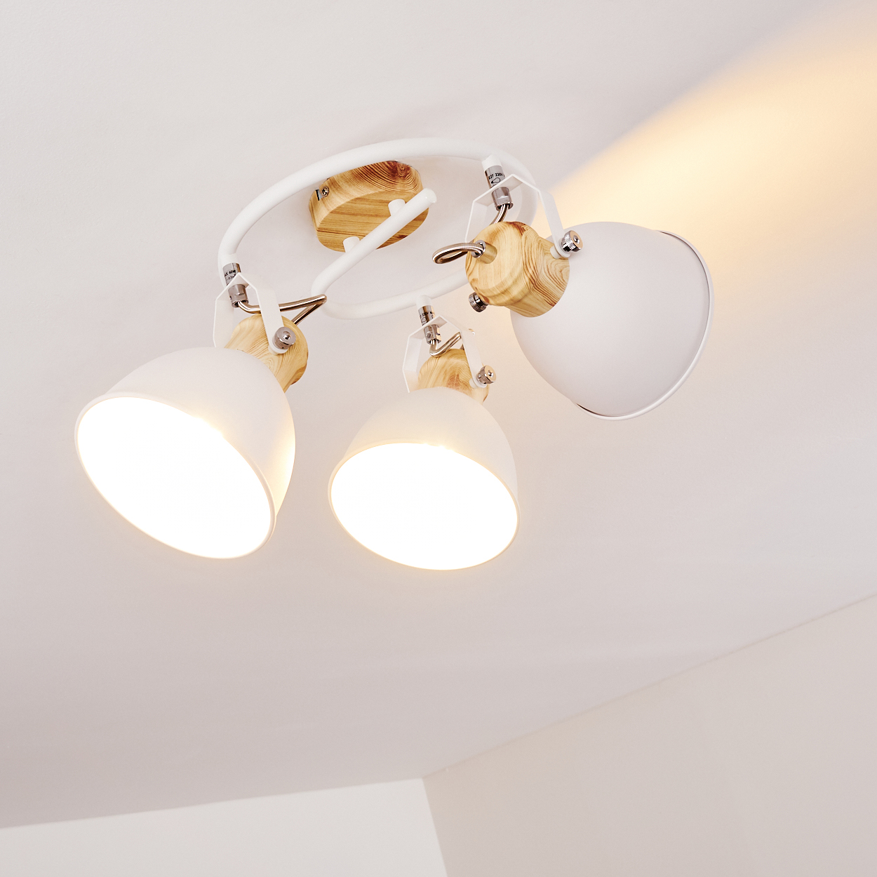 Eine weiße Deckenleuchte mit drei verstellbaren Lampen und Holzakzenten.