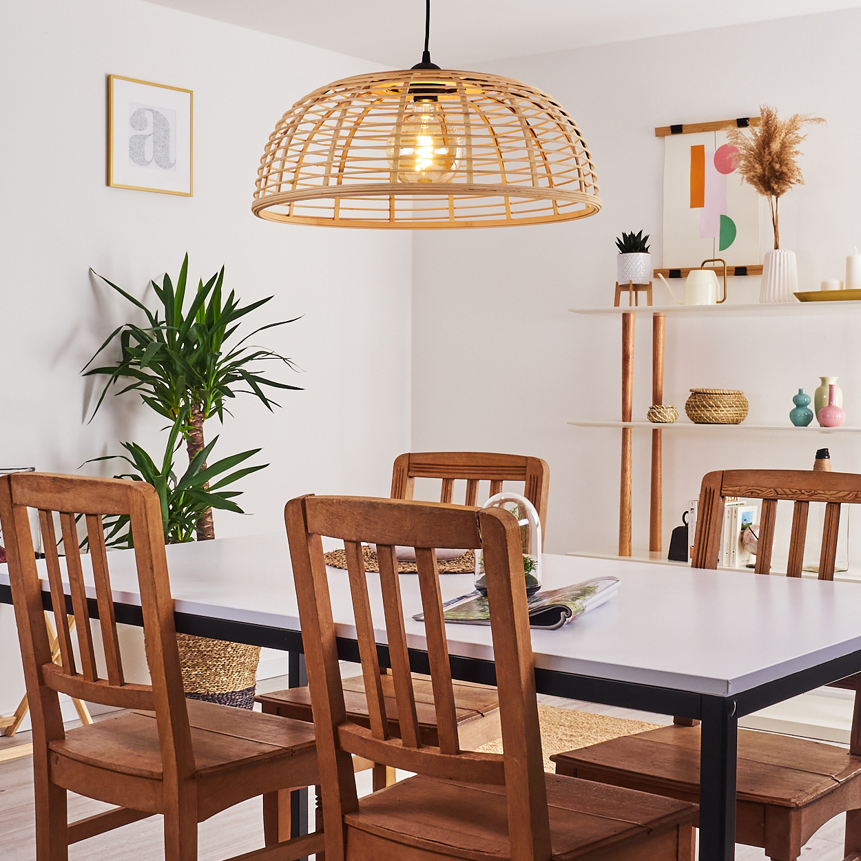 Ein Esszimmer mit Holztischen und Stühlen, einer Hängeleuchte und Pflanzen.