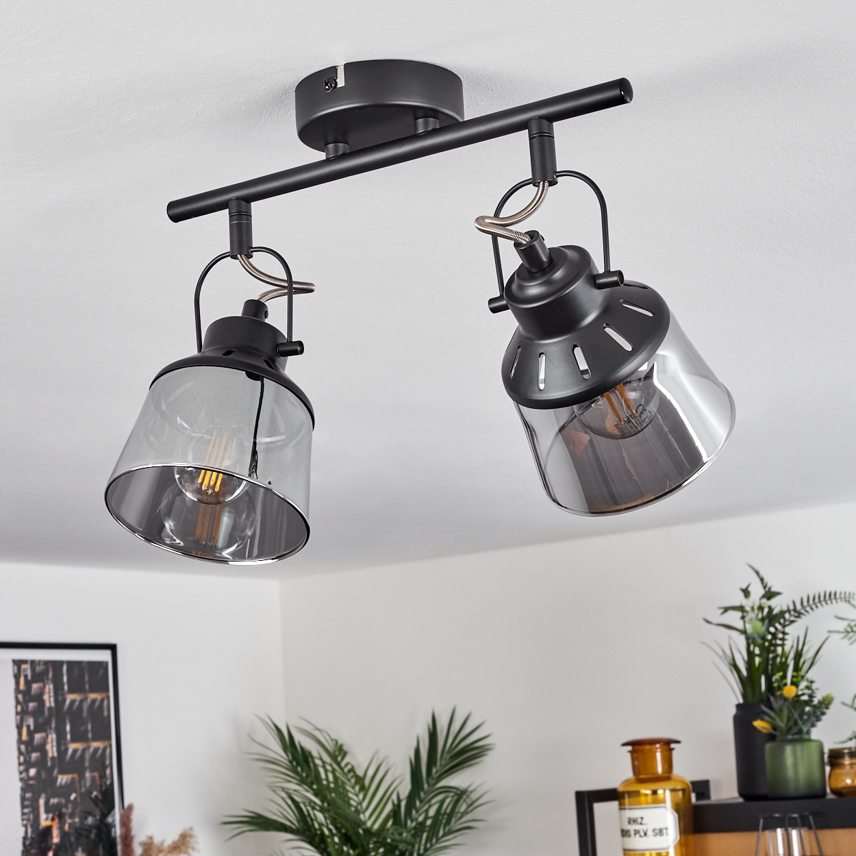 Eine schwarze Deckenleuchte mit zwei rauchglas Lampenschirmen und sichtbaren Glühbirnen.