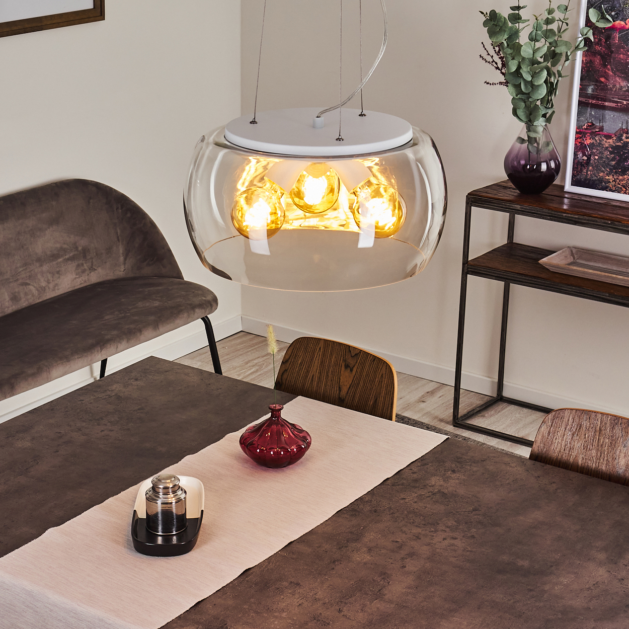 Esstisch mit Hängeleuchte, Sofa, Stuhl, Vase und Bild.