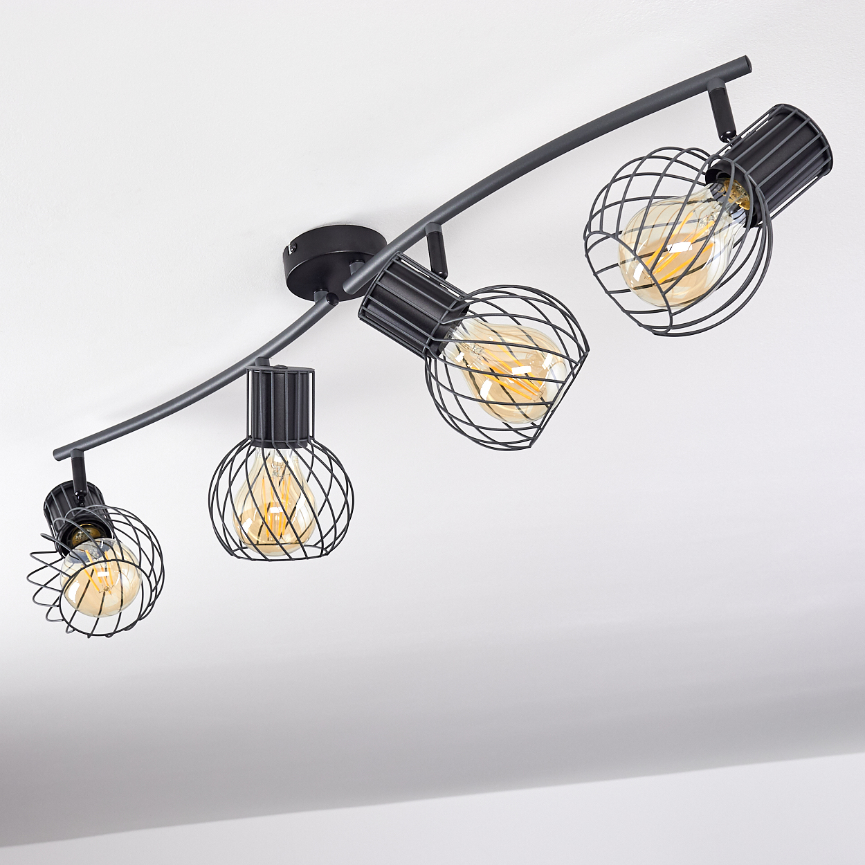 Eine schwarze Schienenleuchte mit vier Lampen und Gitterkäfigen.