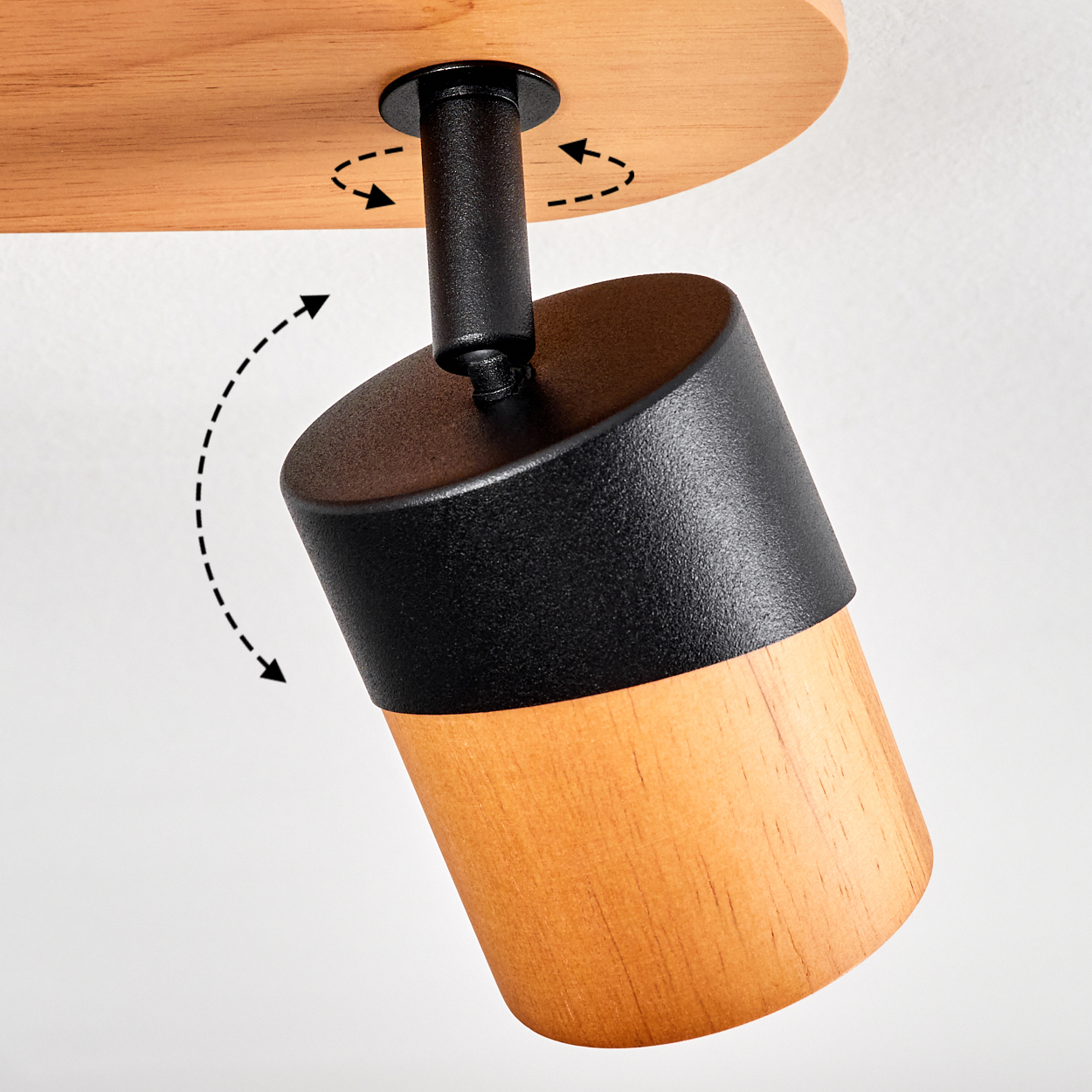 Ein schwenkbarer Lampenkopf aus Holz und schwarzem Metall, an einer Holzdecke befestigt.