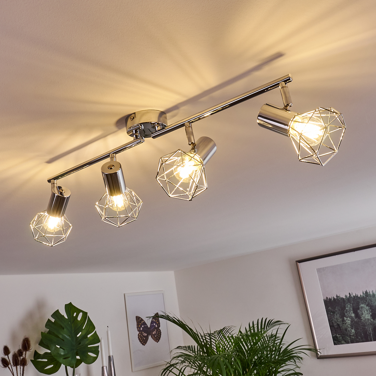 Ein moderner Deckenstrahler mit vier Lampen und geometrischen Metallkäfigen.