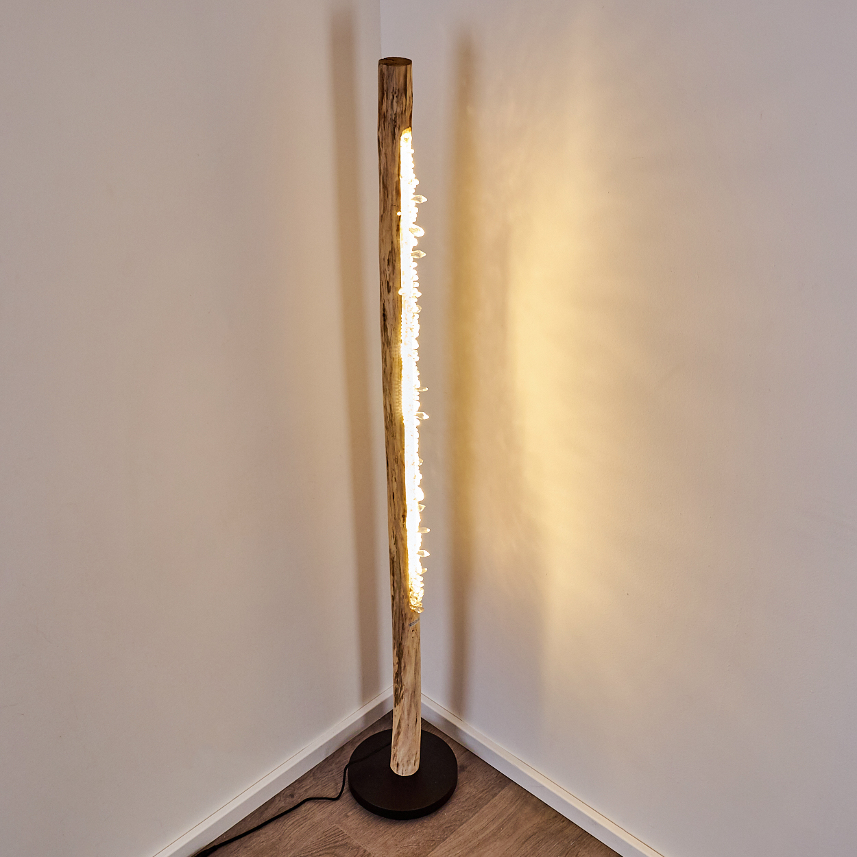 Ein Stehlampenfuß aus Holz mit integrierten Lichtern in einer Hausecke.