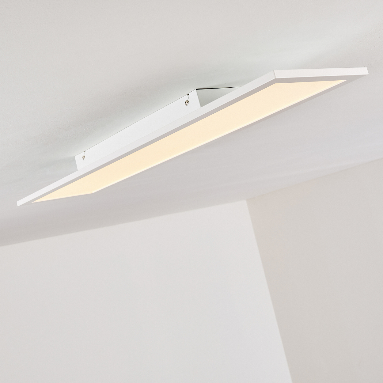 Eine weiße, rechteckige LED-Deckenleuchte mit warmem Licht ist an einer weißen Decke montiert.