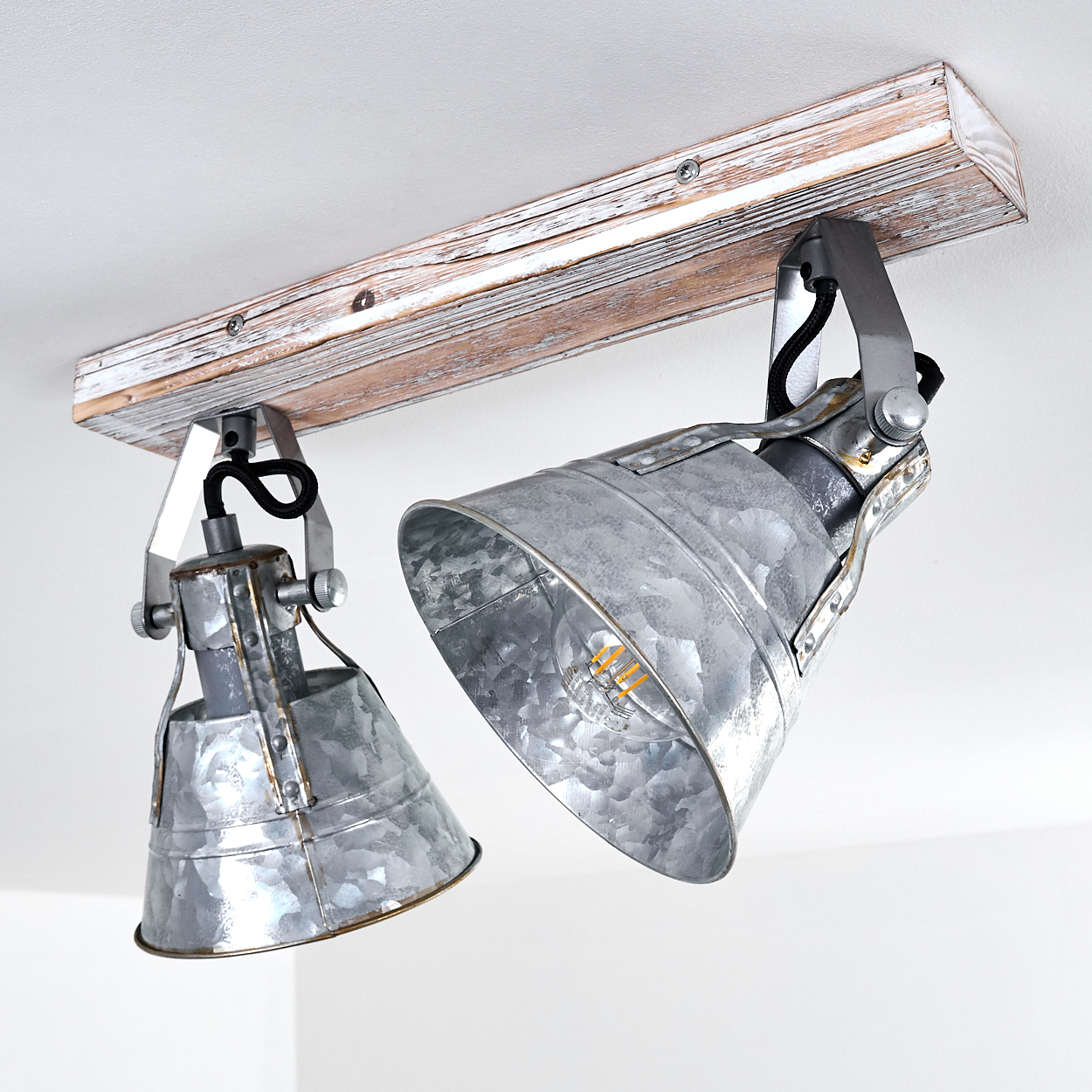 Zwei verzinkte Industrie-Spots hängen an einem Holzbalken an der Decke.