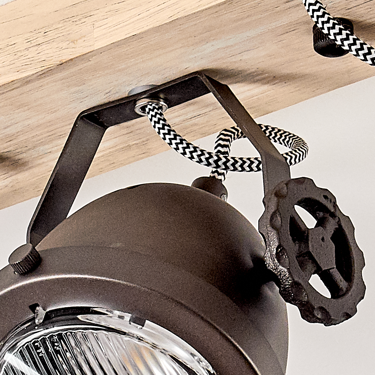 Dunkelbraune Lampe mit Metallarm und Zahnrad an Holzbalken befestigt.