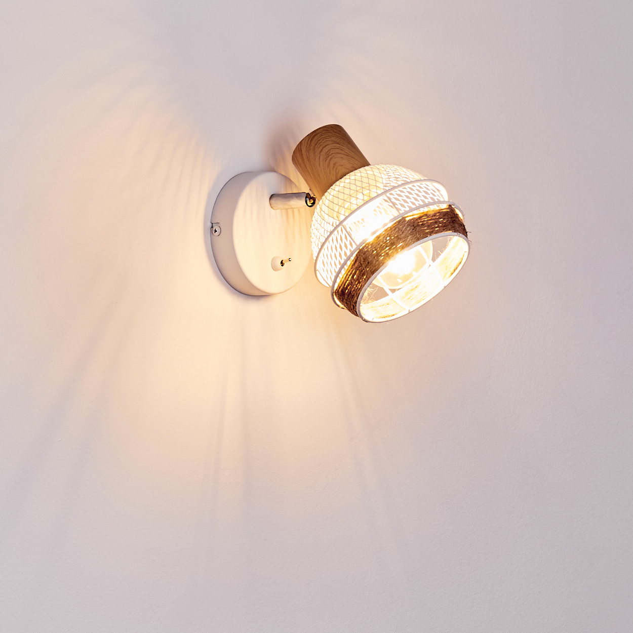 Eine weiße Wandleuchte mit Holzdetails und einem geflochtenen Lampenschirm leuchtet hell.