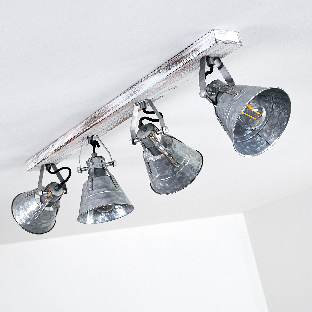 Deckenleuchte mit vier verwitterten Metallkappen auf einem Holzbalken.