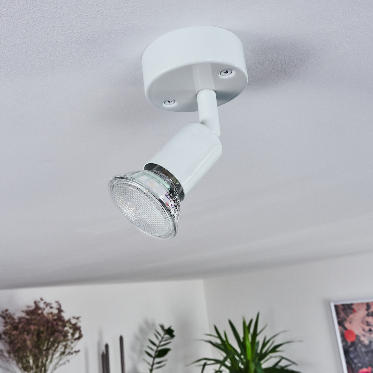 Ein weißer Deckenstrahler mit verstellbarem Kopf ist an der Decke montiert.