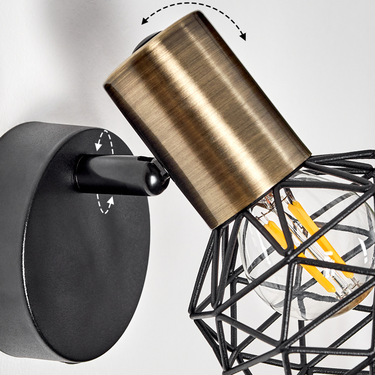 Ein moderner Wandspot mit schwarzem Sockel, Messingarm und Drahtkugel Lampe.