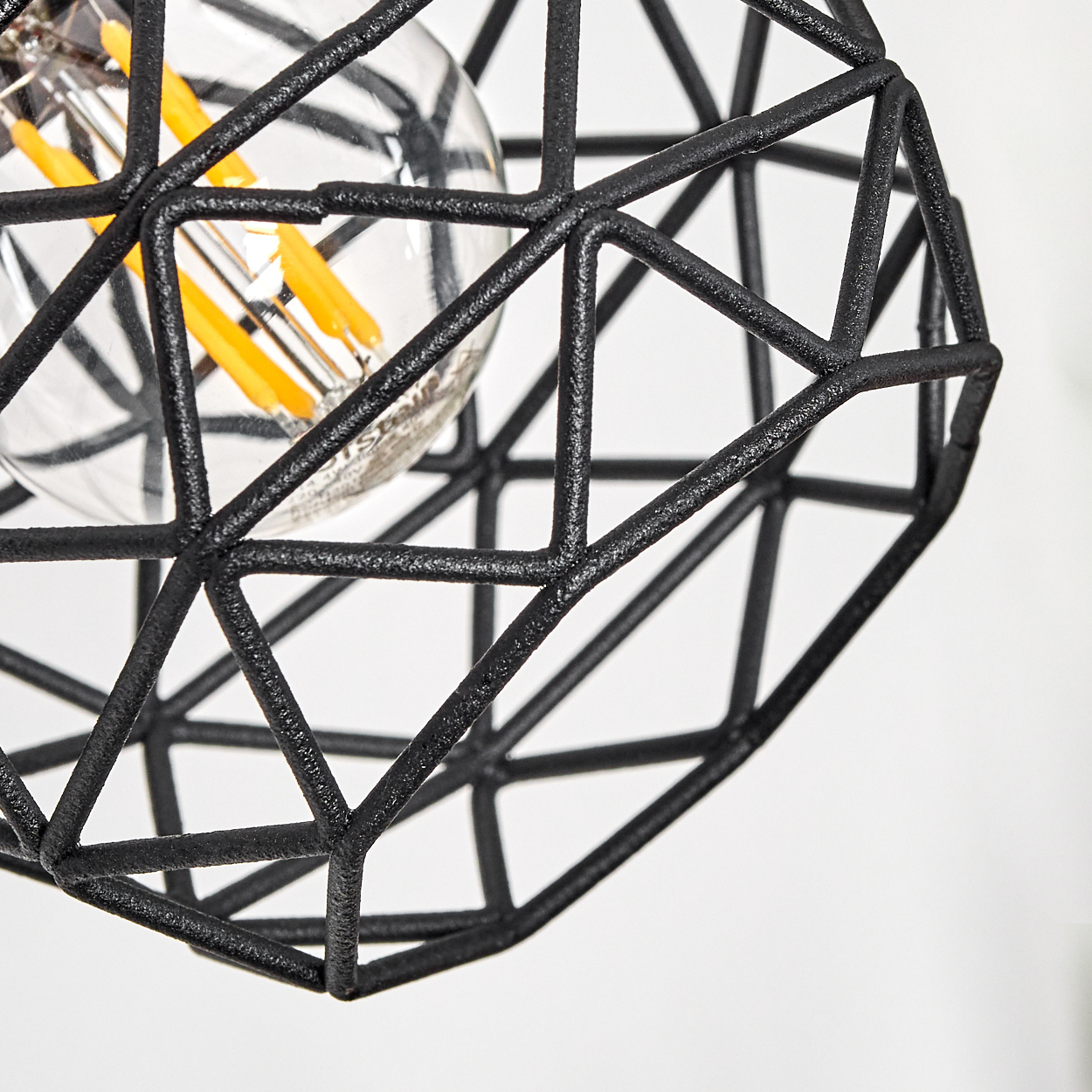 Eine Nahaufnahme einer schwarzen geometrischen Lampe mit sichtbarem Glühfaden.