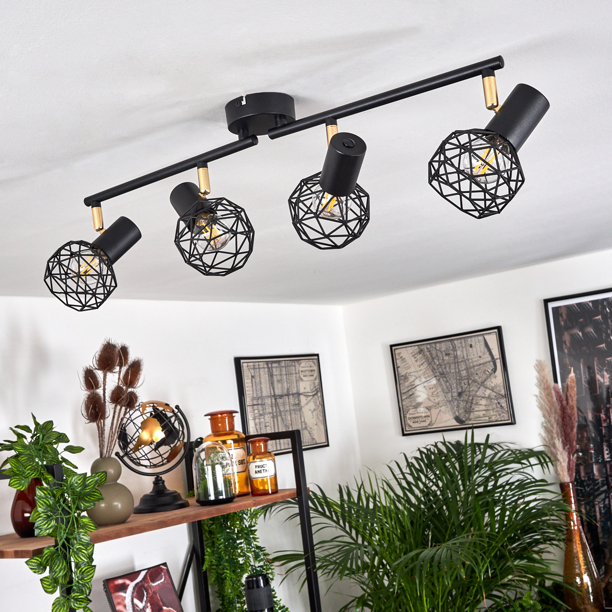 Schwarzer Deckenstrahler mit vier Lampen, geometrischen Käfigschirmen und Goldakzenten.