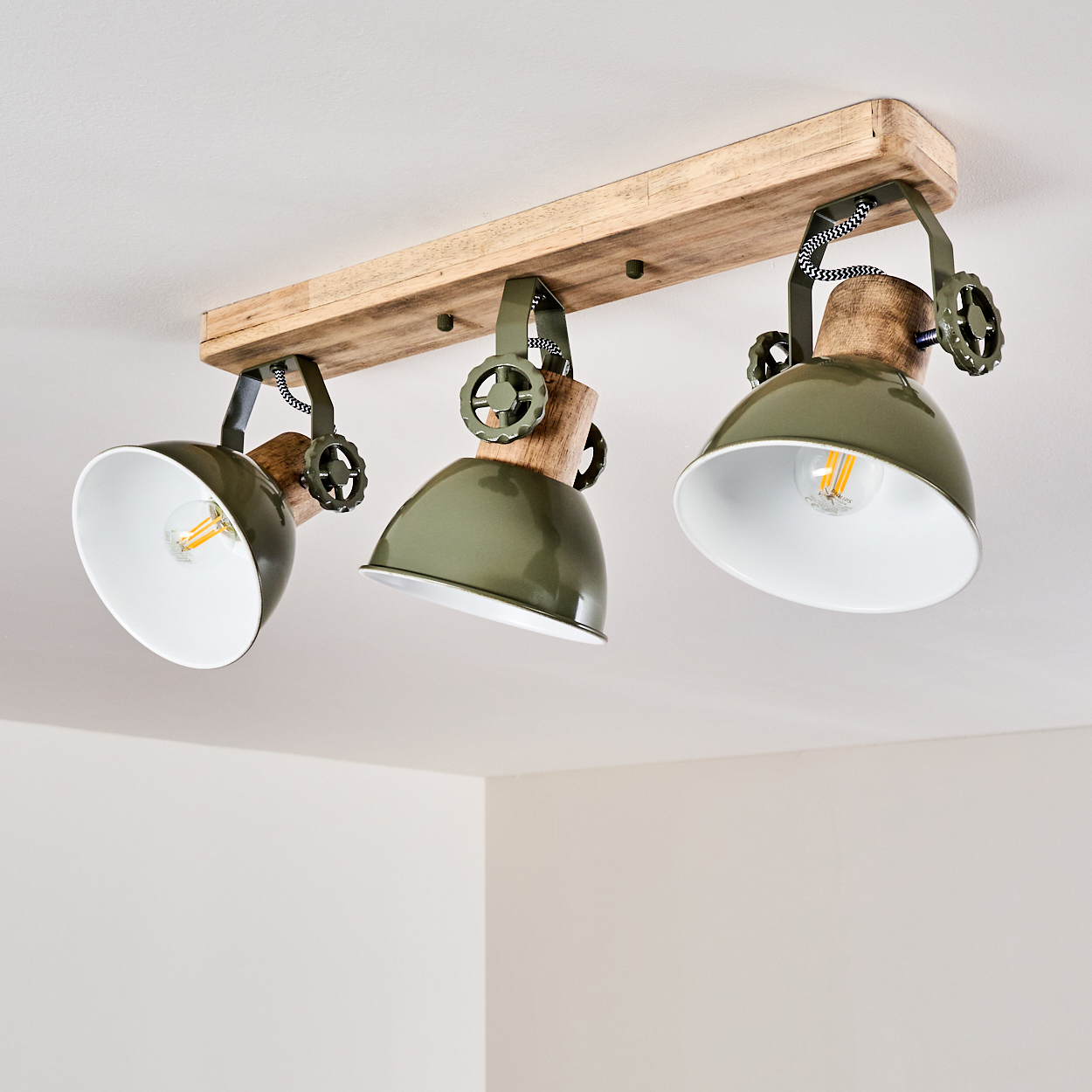 Deckenleuchte mit Holzsockel, drei grünen Lampenschirmen und sichtbaren Glühbirnen.
