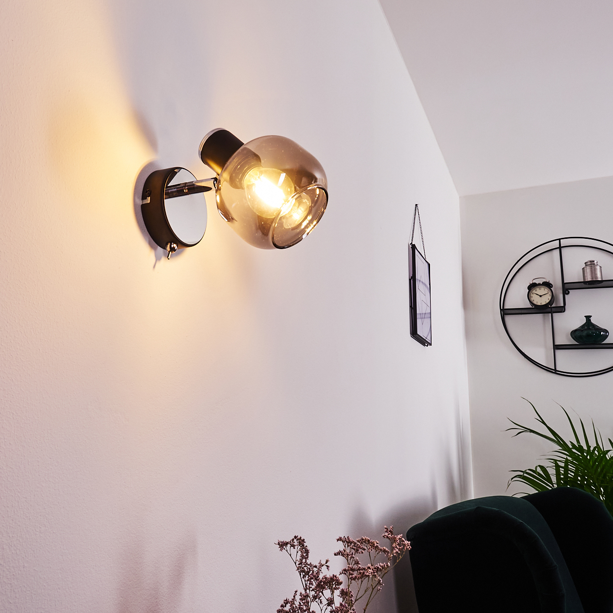 Moderne Wandleuchte mit bronzefarbenem Glas und Glühbirne an weißer Wand.