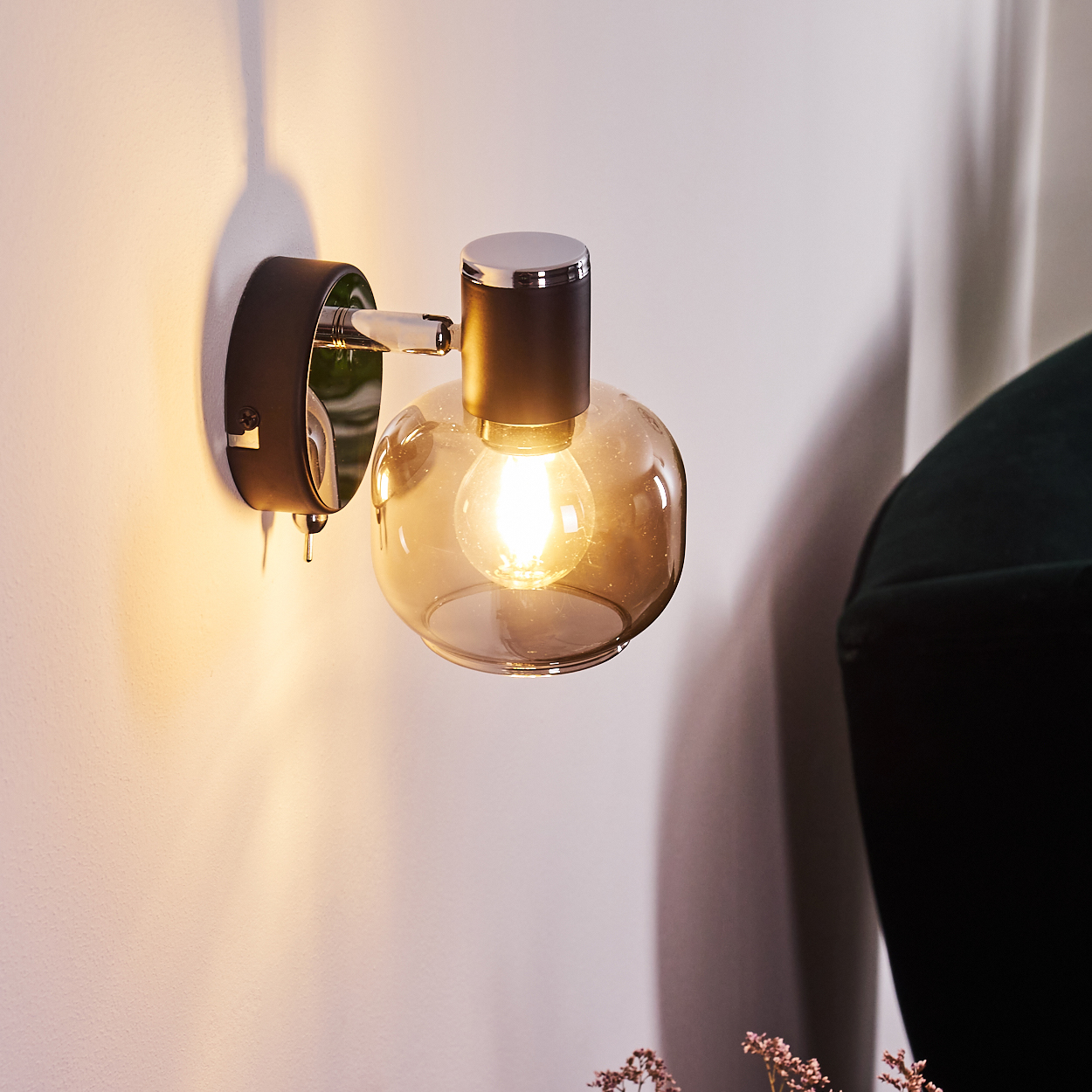 Eine Wandleuchte mit einem rauchfarbenen Glas und einem Glühbirnenlicht.