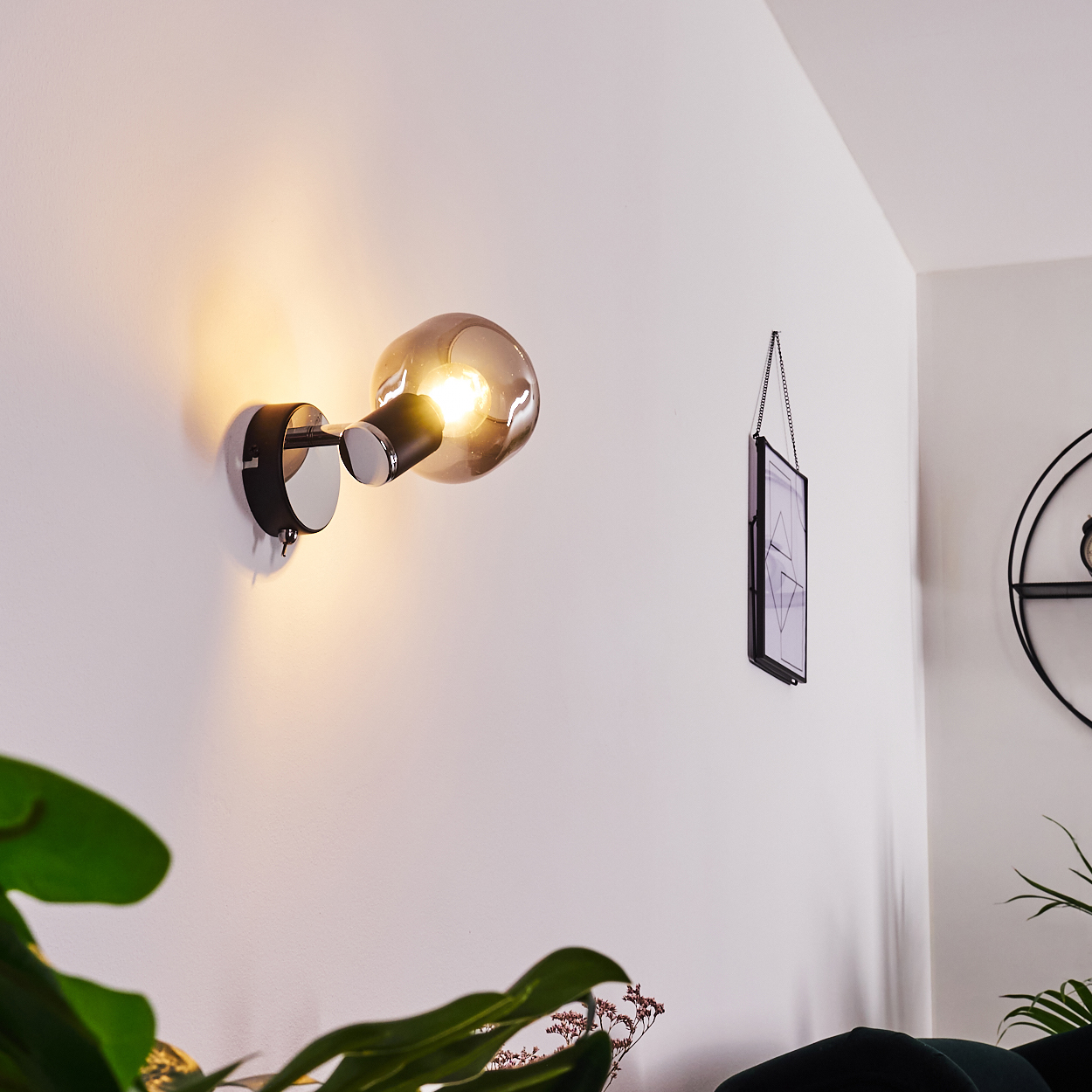 Eine moderne Wandleuchte mit rauchglas schirm beleuchtet eine weiße Wand.
