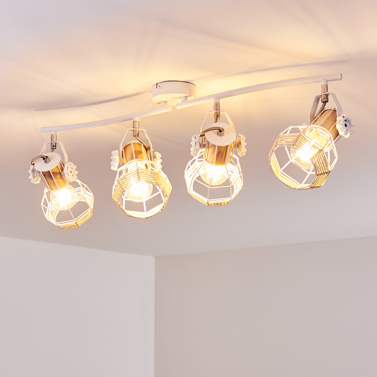 Eine weiße Schienenleuchte mit vier Lampen, jede mit einem dekorativen Käfig.