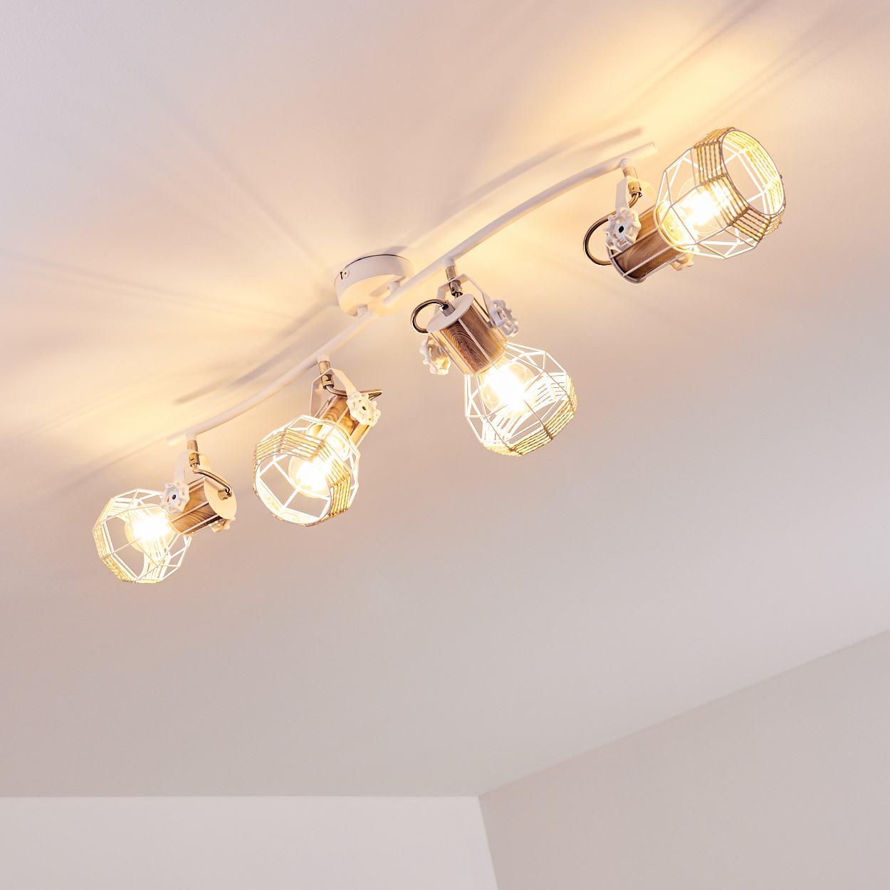 Eine weiße Deckenleuchte mit vier Lampen, jede mit einem Drahtkorb und Holzdetails.