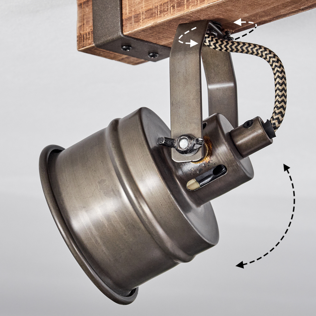 Eine verstellbare Industrieleuchte mit Metallschirm hängt an einem Holzbalken.