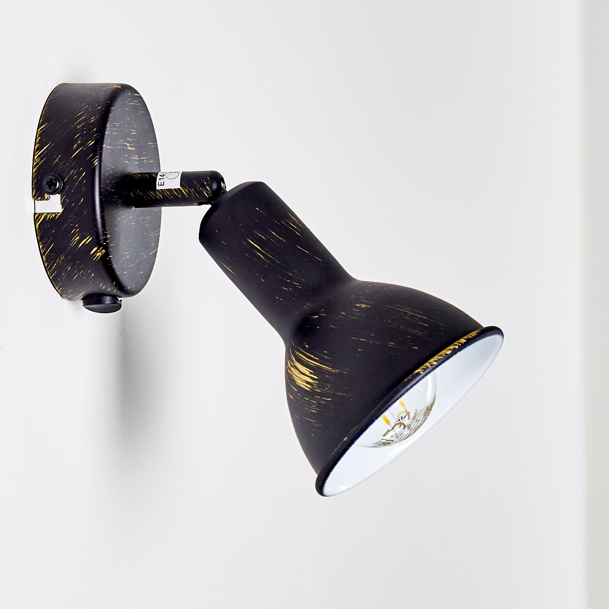 Eine schwarze Wandlampe mit goldenen Spritzern, verstellbarem Kopf und sichtbarer Glühbirne.