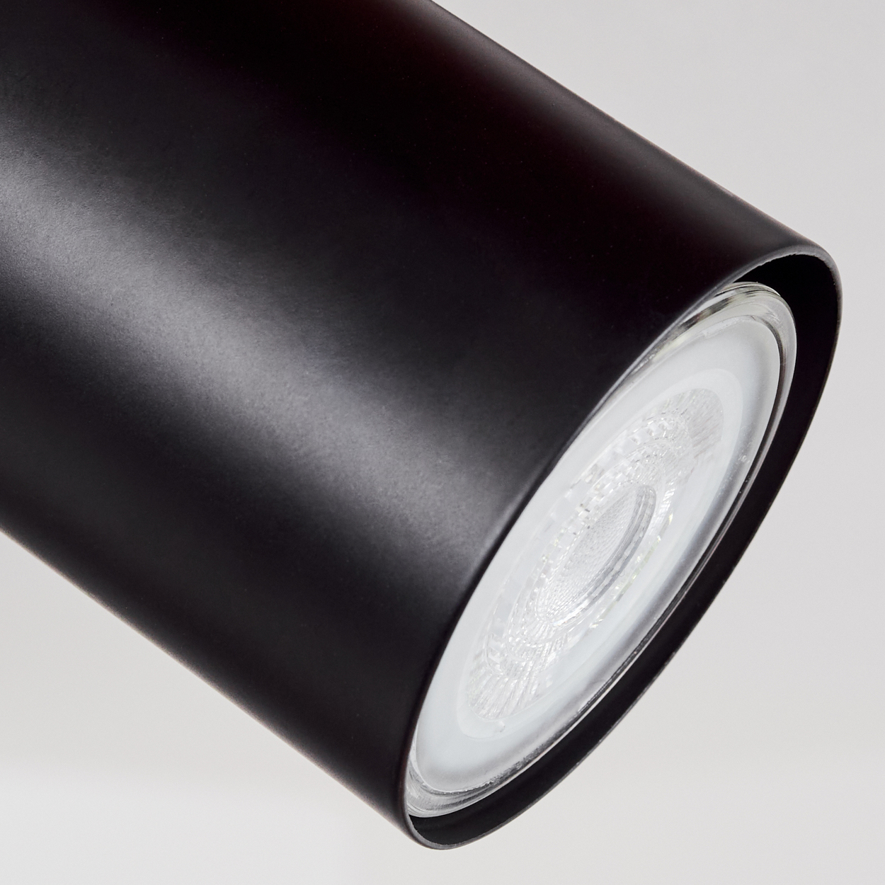 Schwarzer zylindrischer Spot mit weißem LED-Licht und klarem Glas.