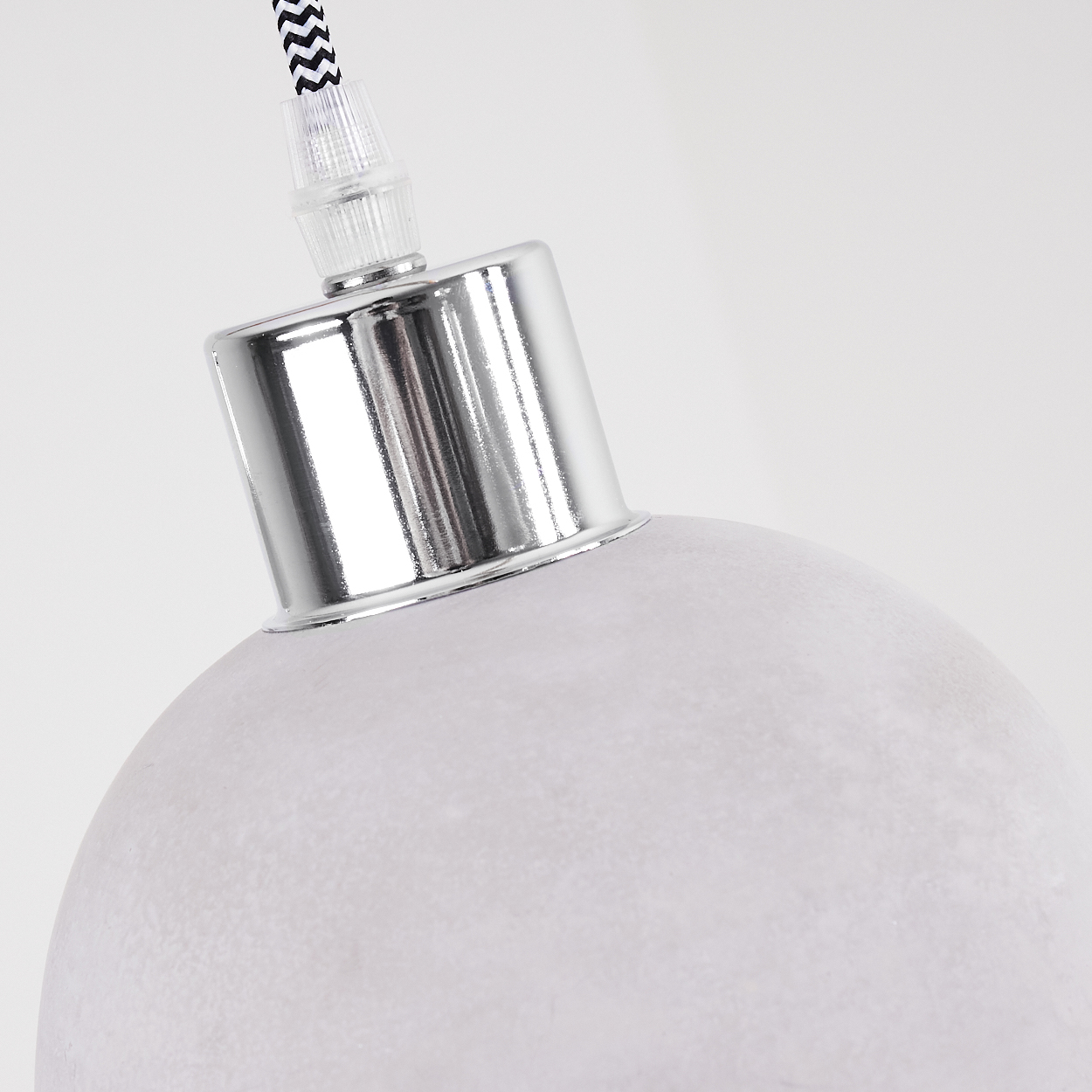 Nahaufnahme einer grauen Lampe mit glänzendem silbernem Metallakzent am Aufhängungsdetail.