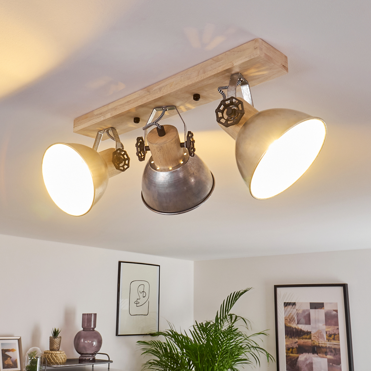 Holzbalken mit drei verstellbaren Metallstrahlern in Gold und Silber.