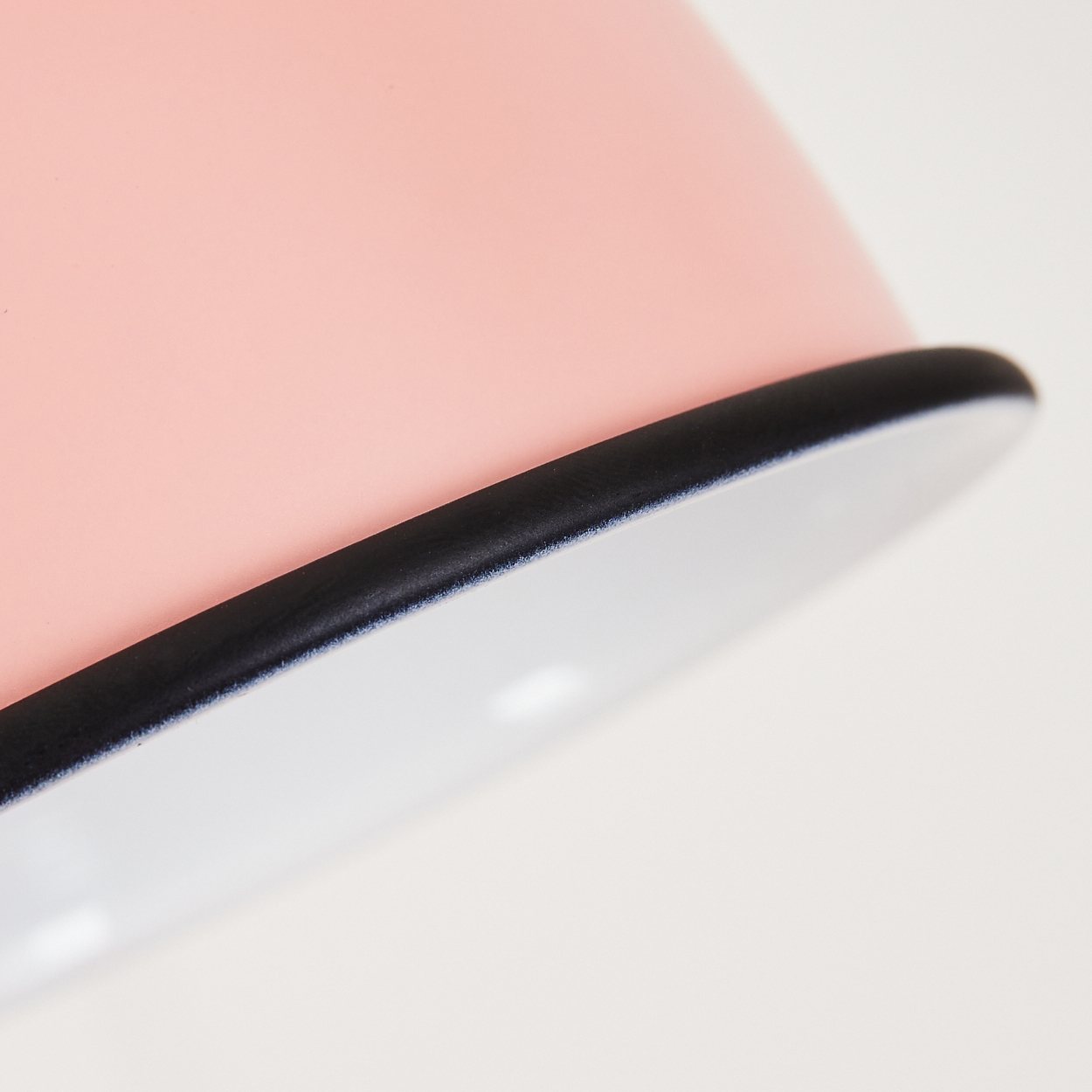 Nahaufnahme einer rosa Schale mit schwarzem Rand und weißem Inneren.