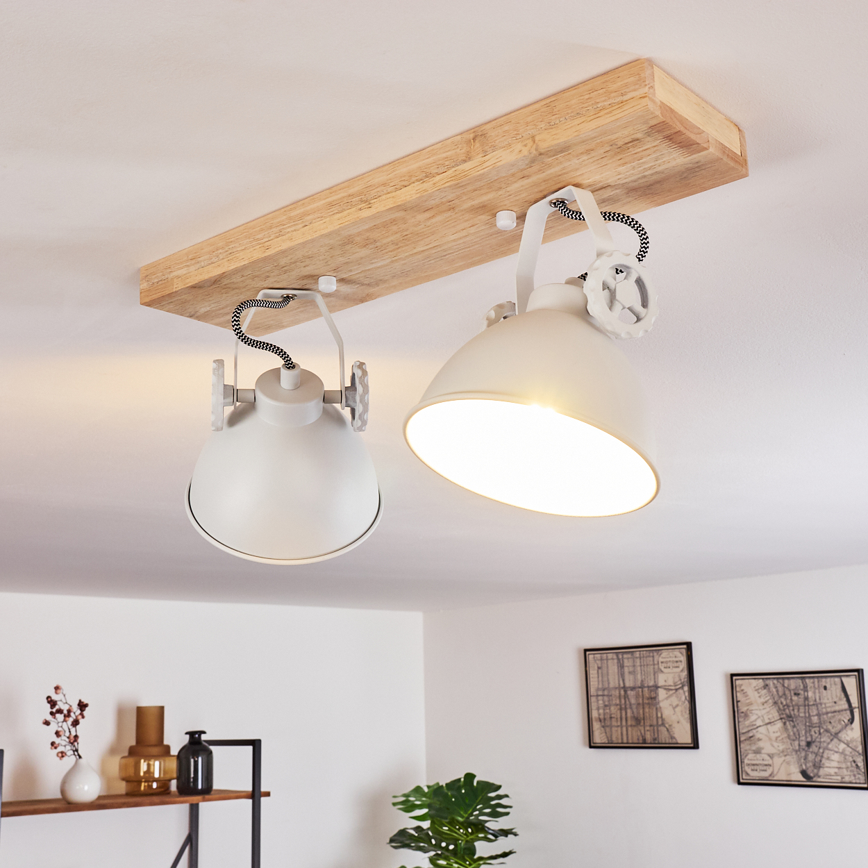 Zwei weiße Pendelleuchten an Holzbalken über einem Regal mit Vasen und Bildern.