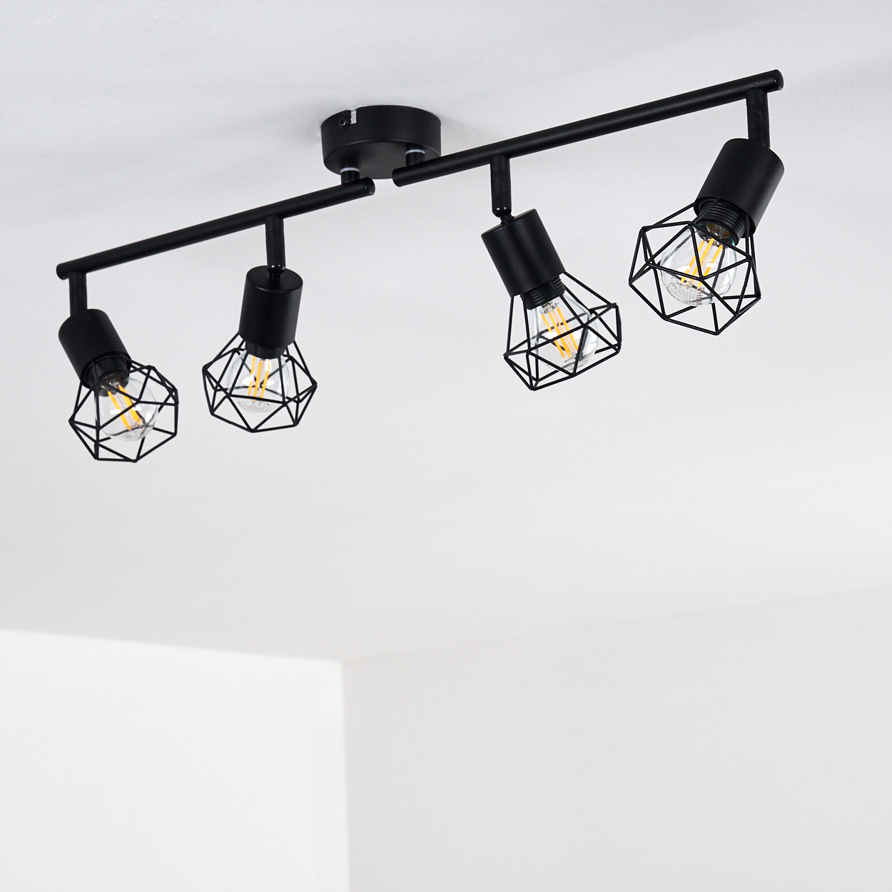 Schwarzer Deckenstrahler mit vier Lampen mit geometrischen Käfigschirmen.