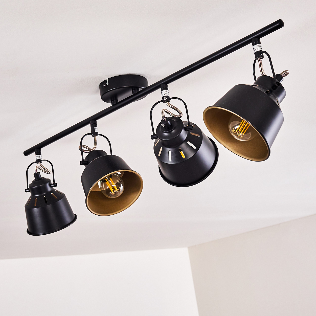 Schwarze Deckenleuchte mit vier verstellbaren Spots, goldene Innenseiten.