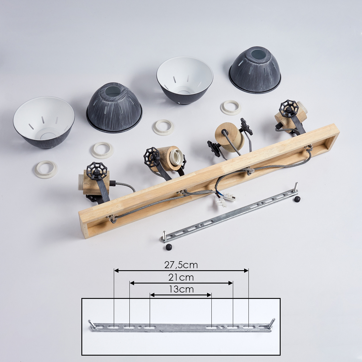 Ein Holzbalken mit drei Lampenfassungen, Lampenschirmen und Befestigungsteilen.