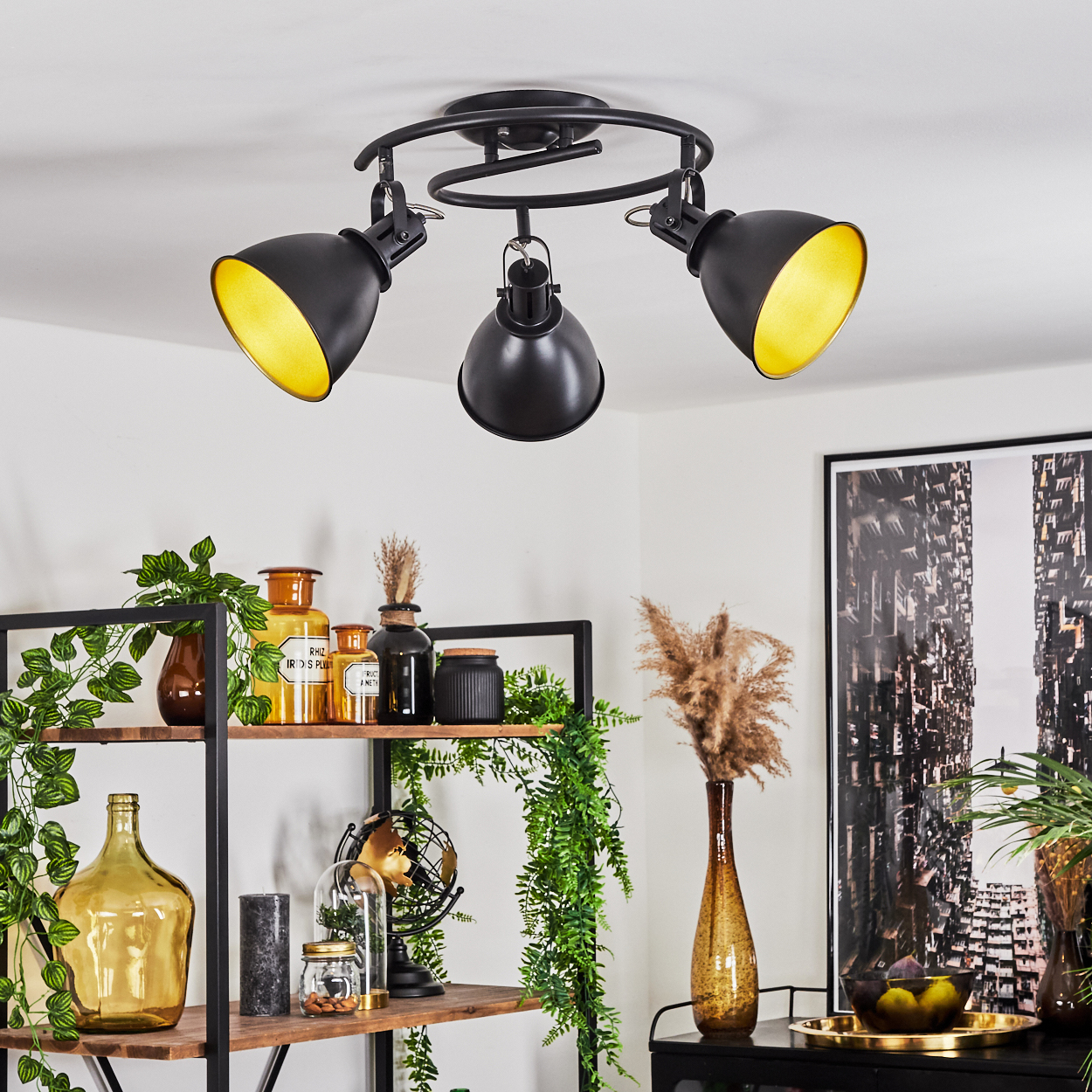 Eine schwarze Deckenleuchte mit drei verstellbaren Lampen mit gelben Innenseiten.