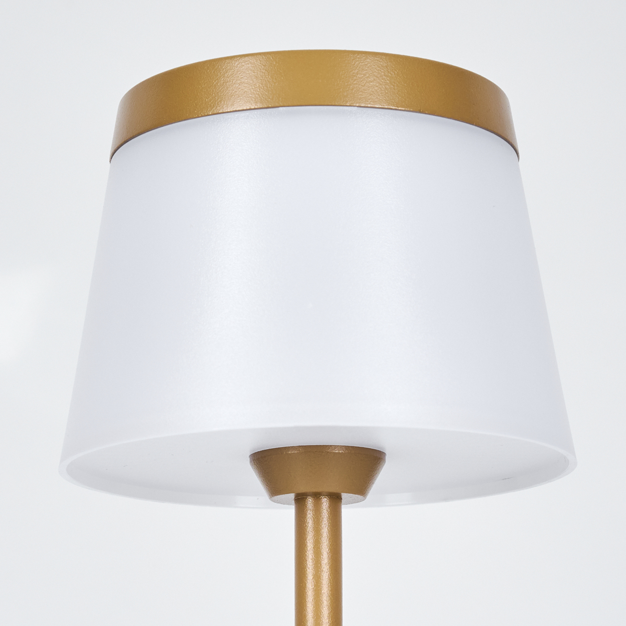 Eine weiße Lampe mit goldenem Rand und Sockel.