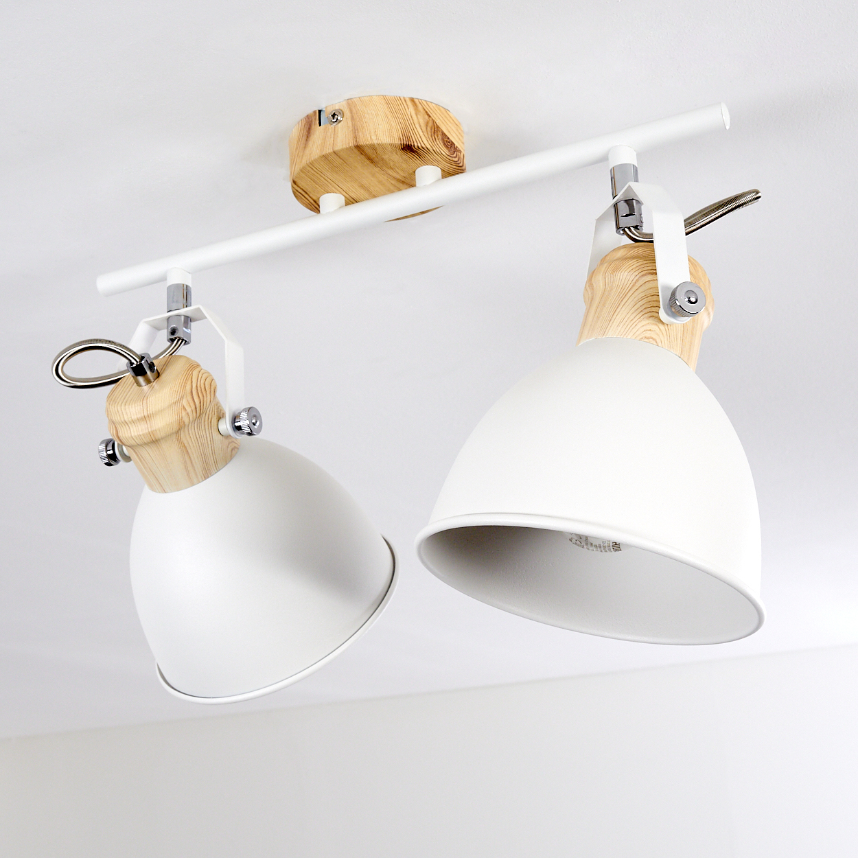 Zwei weiße Lampenschirme mit Holzdetails an einer weißen Stange an der Decke.