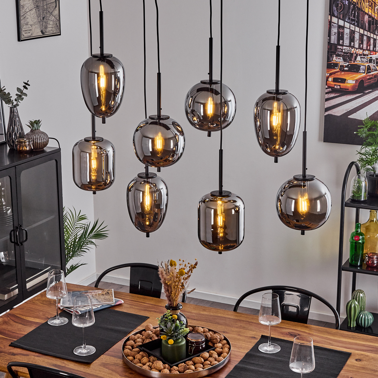 Ein Esstisch mit acht rauchglas Pendelleuchten mit Glühbirnen.