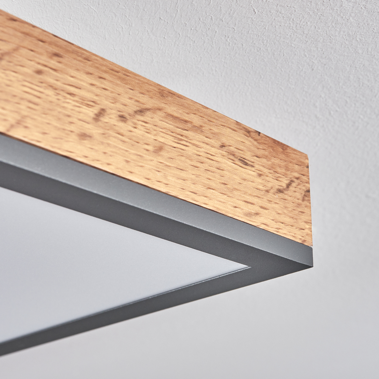 Holzbalken mit grauem Rahmen und diffuser Lichtplatte darüber.