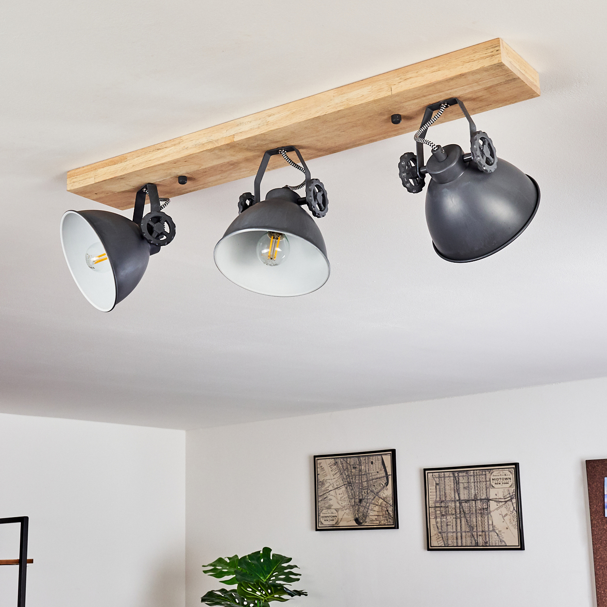 Drei graue Lampenschirme an einem Holzbrett an der Decke.