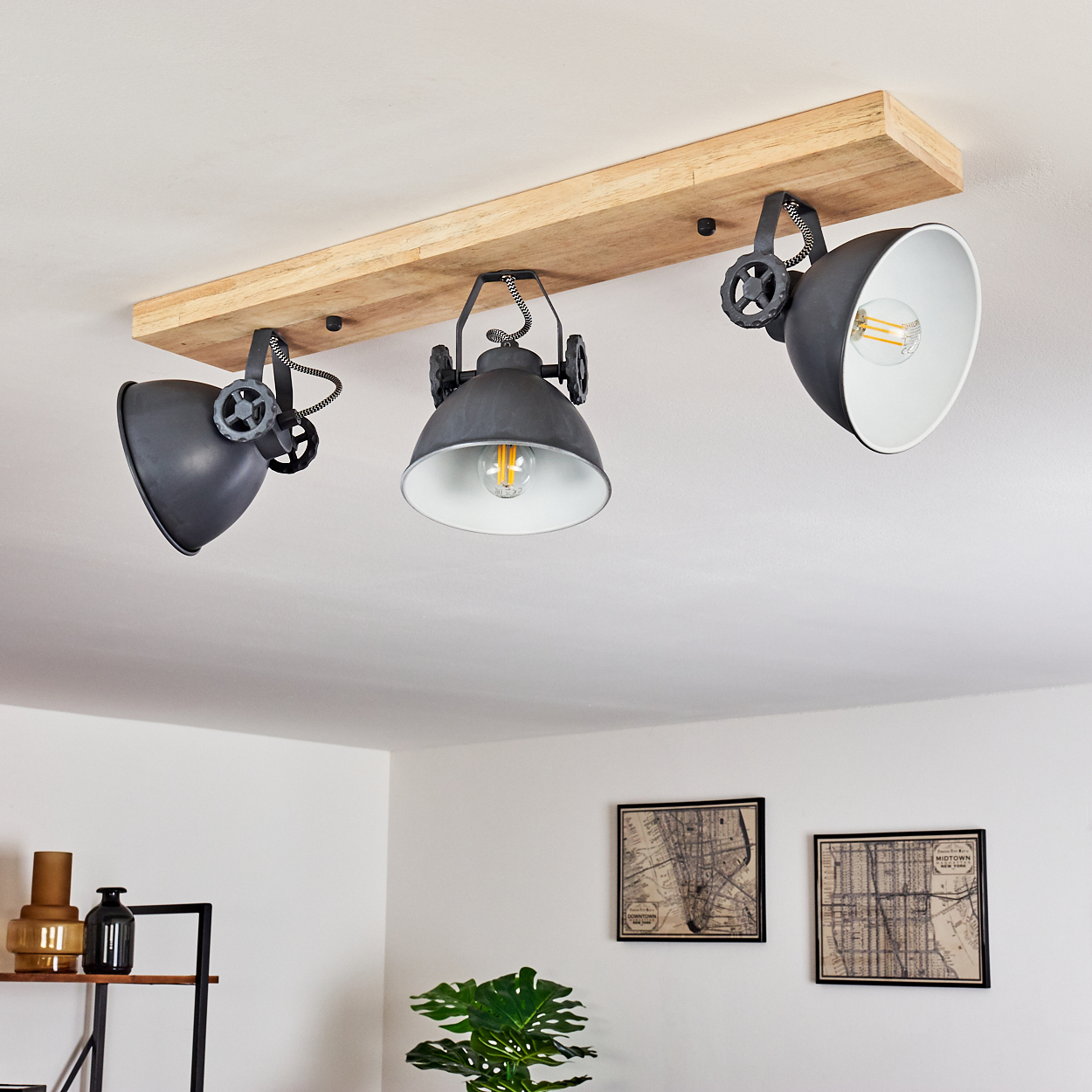 Drei industrielle Pendelleuchten an einem Holzbalken an der Decke.