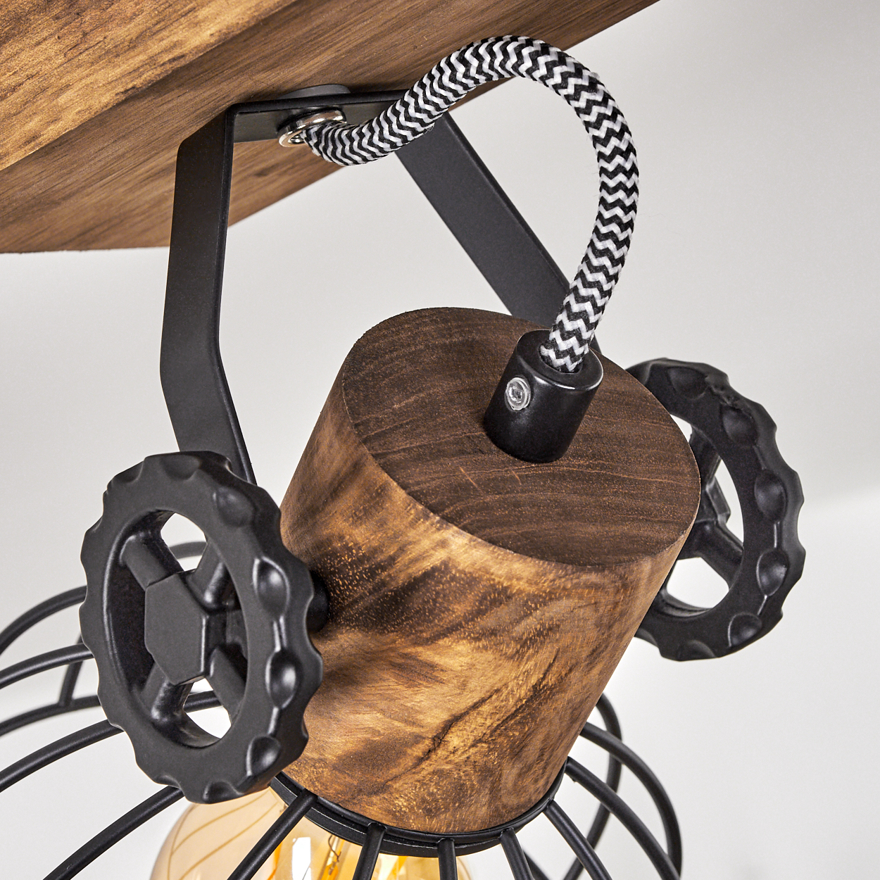 Eine Lampe mit Holzdetails, schwarzem Metall und einem Glühbirnenkäfig.