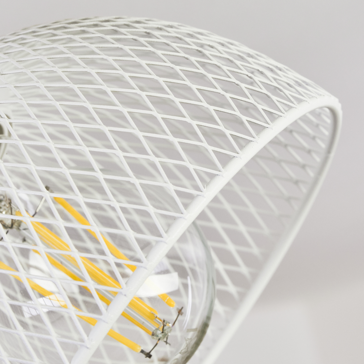 Eine weiße Gitterlampe mit sichtbarem Glühfaden und gelben LED-Streifen.