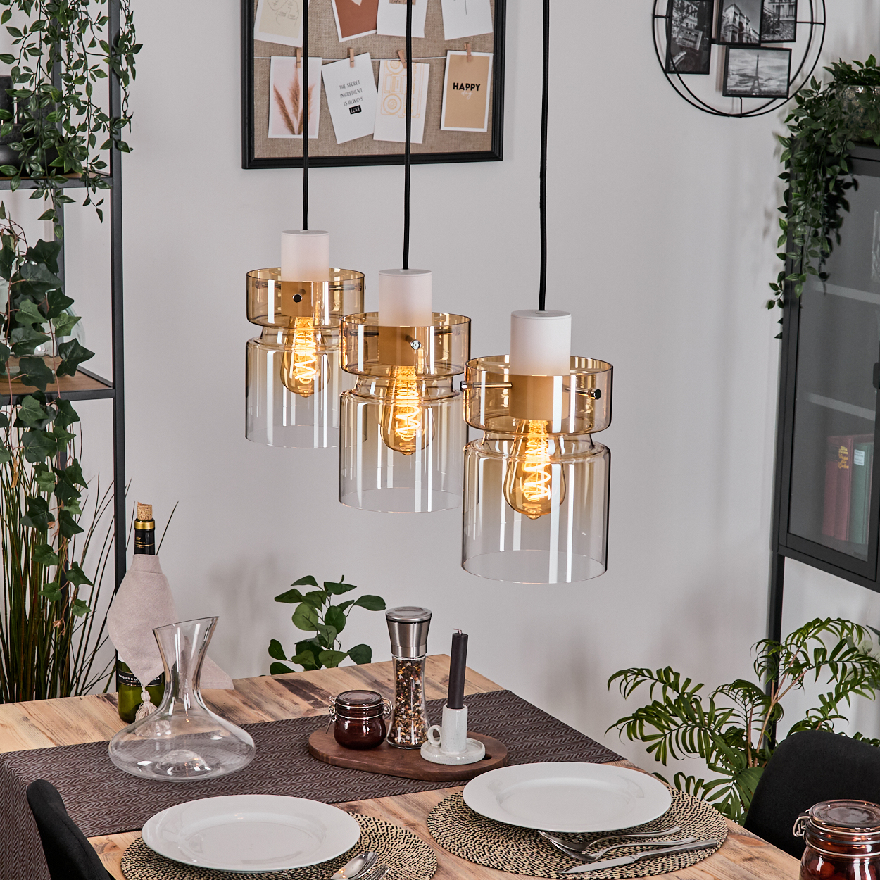 Esszimmer mit Hängelampen, Holztisch, Geschirr und Pflanzen.
