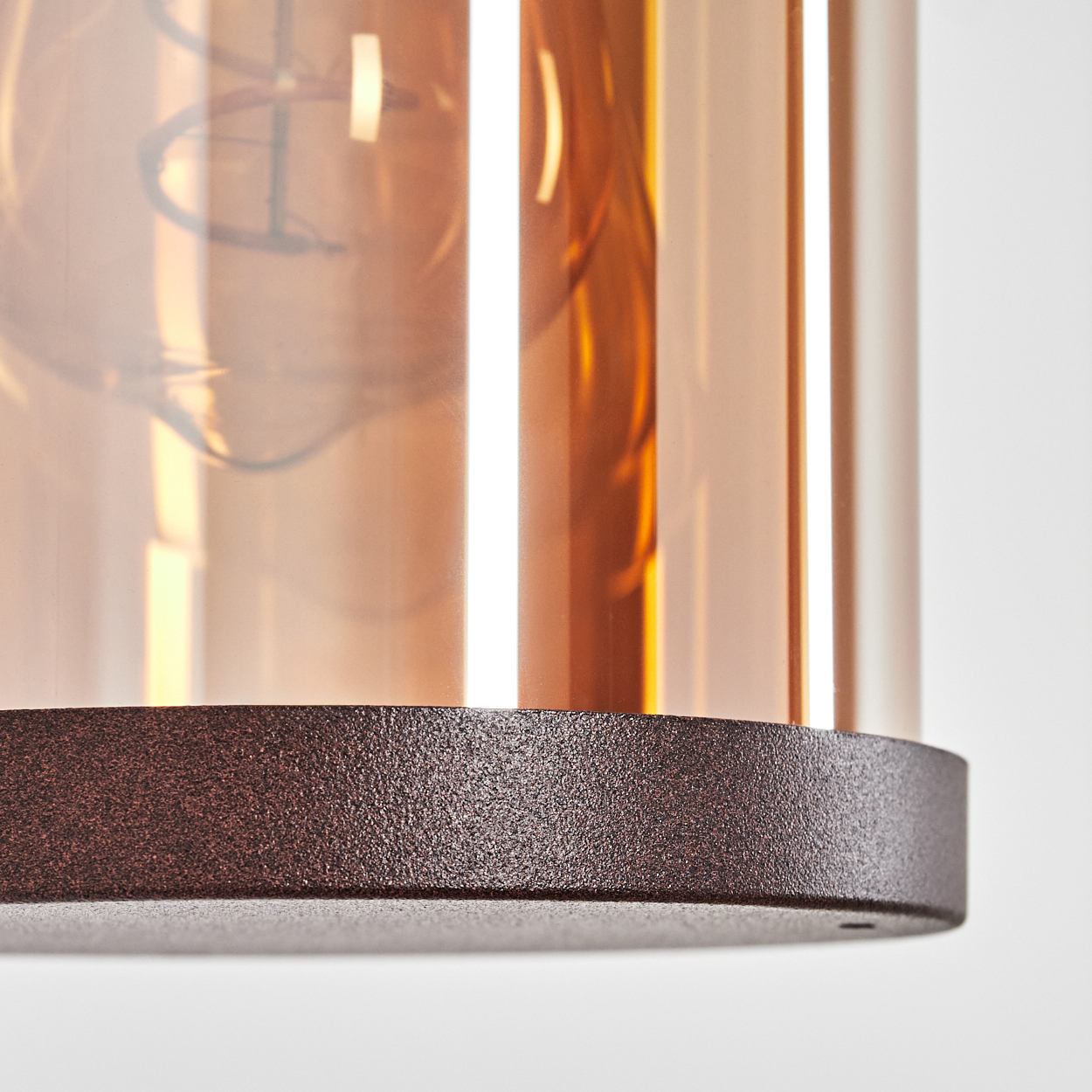 Nahaufnahme einer bronzefarbenen Lampe mit Glühbirne und Glaszylinder.